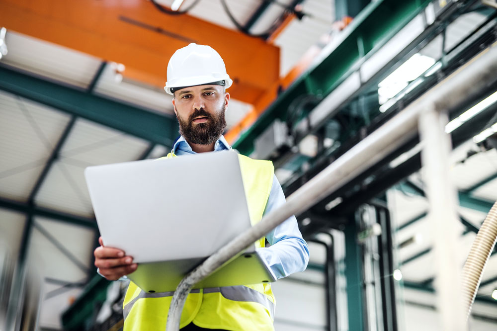 Male engineer with laptop looking into production cycle time