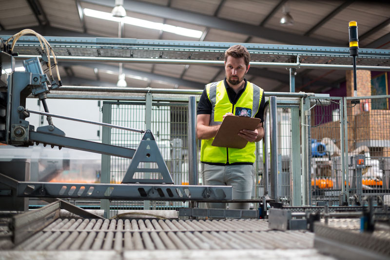 Worker maintaining record on clipboard in fully automated factory