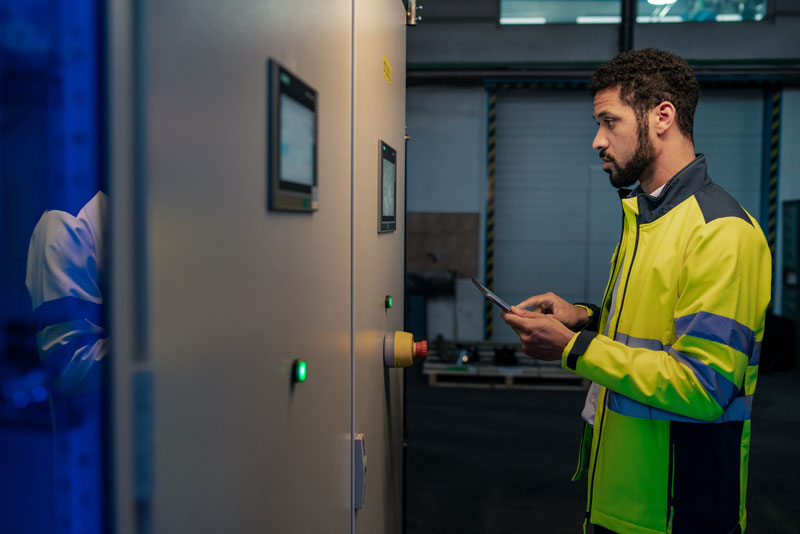 Young industrial worker operating CNC machine based on machine data monitoring software