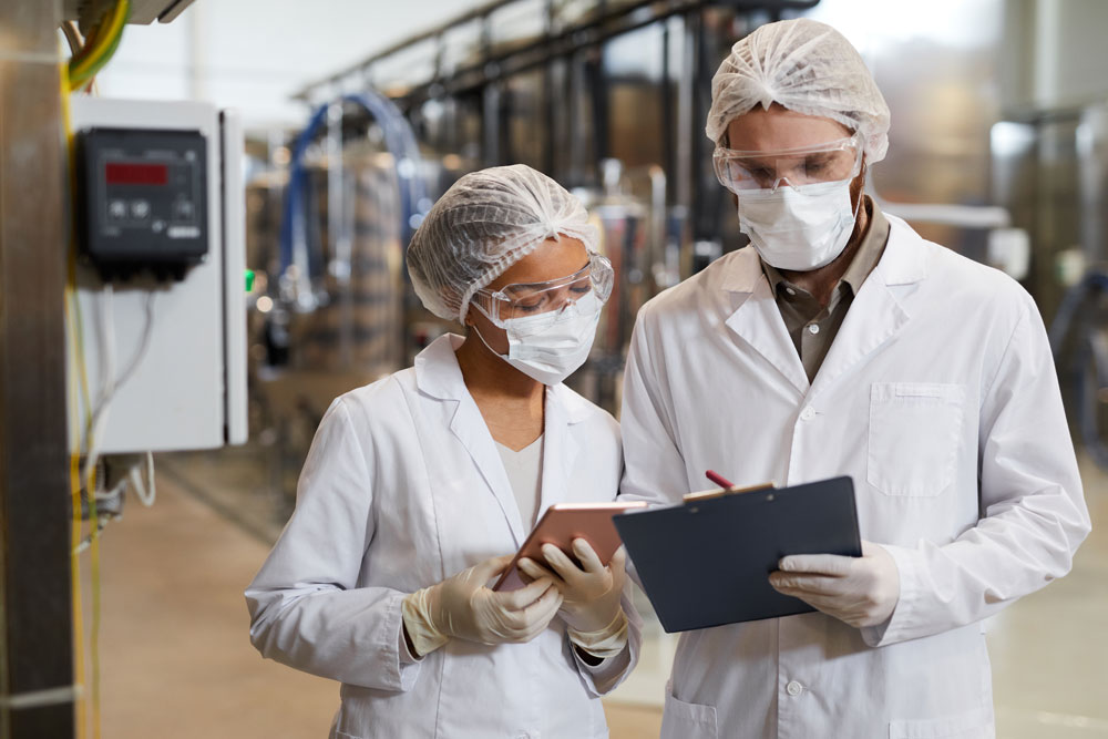 Young workers at pharmaceutical production reviewing control charts