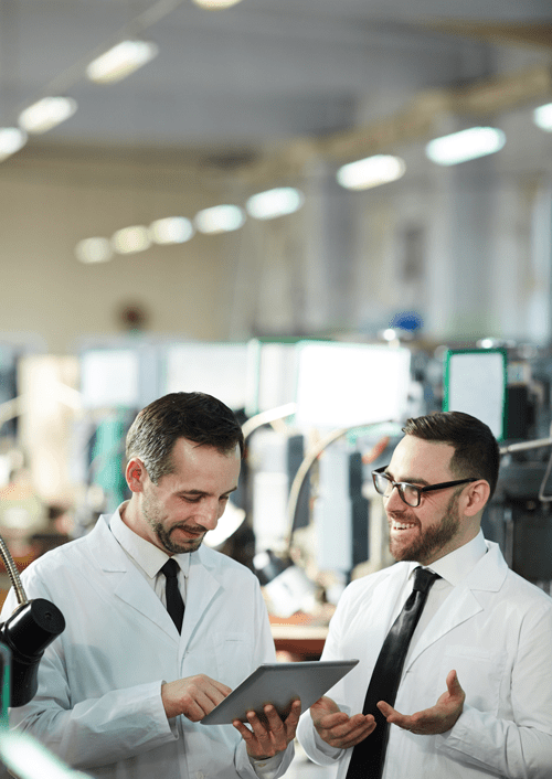 Workers at modern manufacturing factory looking at production monitoring software